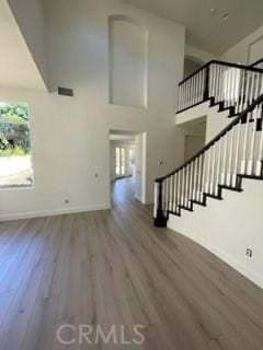 staircase featuring a towering ceiling and wood-type flooring