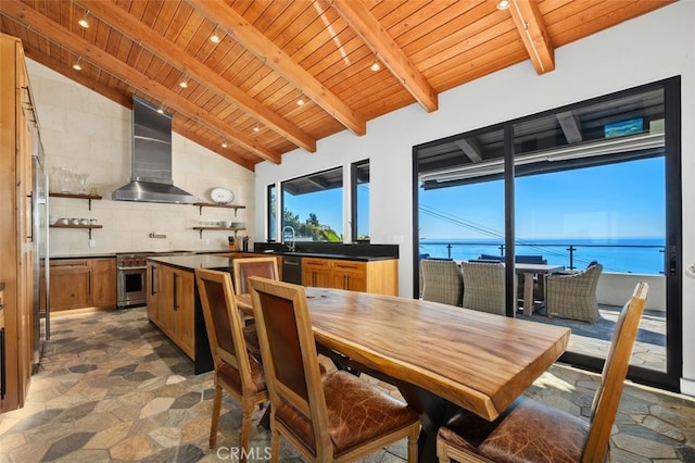 dining space featuring lofted ceiling with beams, a water view, sink, and wood ceiling