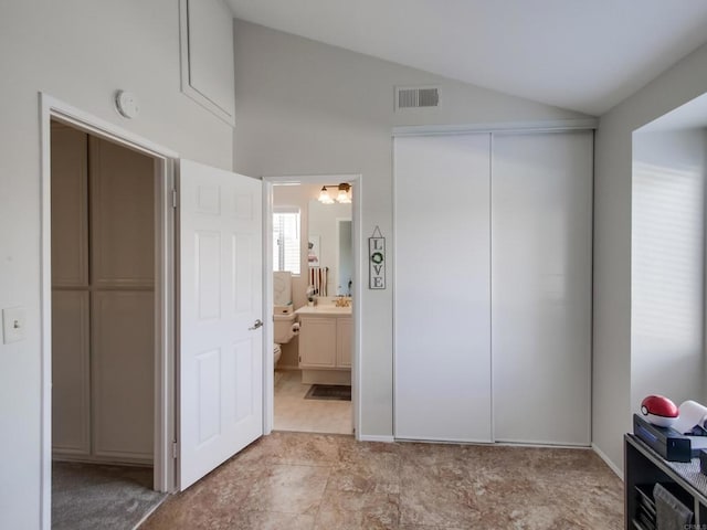 bedroom with vaulted ceiling, ensuite bathroom, and a closet