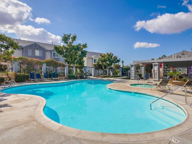 view of swimming pool with a hot tub and a patio area