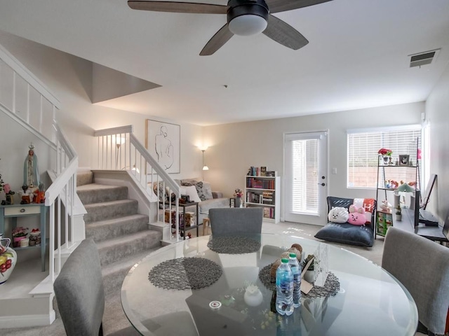 dining area featuring visible vents, ceiling fan, and stairs