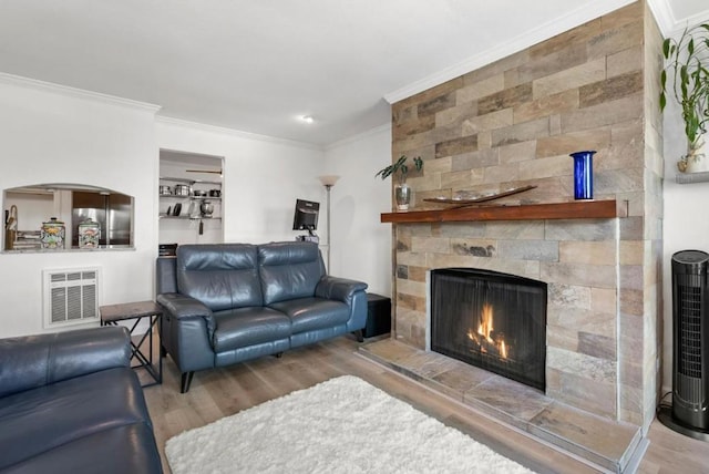 living room with a fireplace, ornamental molding, and wood-type flooring