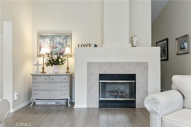 sitting room with a tile fireplace and light wood-type flooring