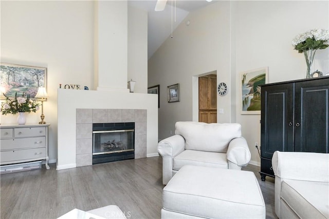 living room featuring hardwood / wood-style flooring, a tiled fireplace, and high vaulted ceiling