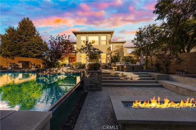 pool at dusk featuring a patio area and a fire pit