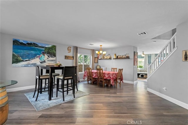 dining room with visible vents, baseboards, stairway, an inviting chandelier, and wood finished floors