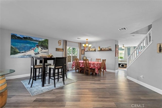 dining area with visible vents, wood finished floors, stairway, an inviting chandelier, and baseboards