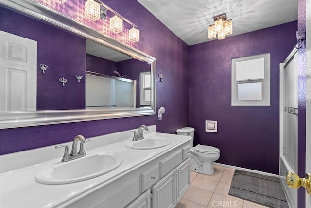 bathroom with a sink, a shower with door, toilet, and tile patterned flooring