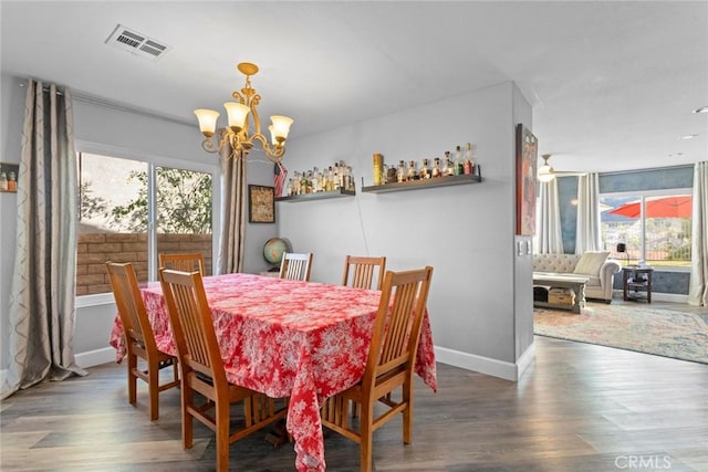 dining space featuring a notable chandelier, visible vents, baseboards, and wood finished floors