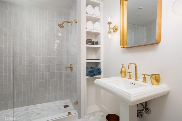 bathroom featuring a tile shower, sink, and built in shelves