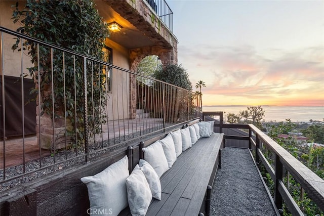 balcony at dusk with a water view, grilling area, and an outdoor living space