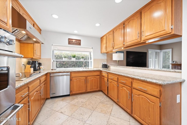 kitchen featuring light stone counters, stainless steel appliances, kitchen peninsula, and sink