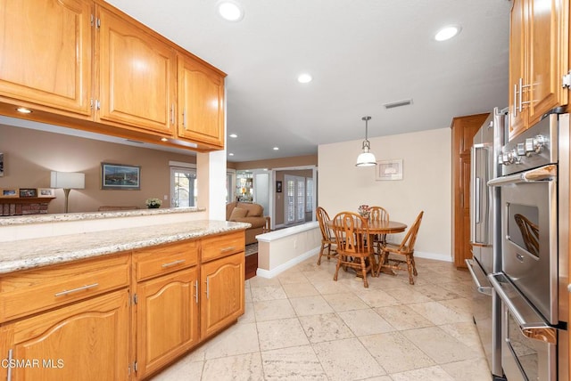 kitchen featuring pendant lighting, stainless steel double oven, and light stone countertops