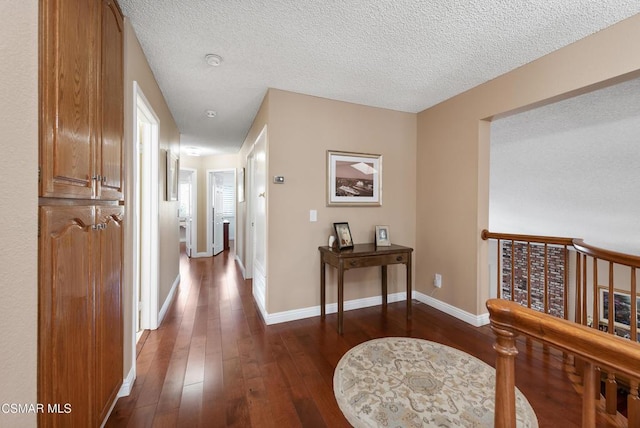 corridor with dark hardwood / wood-style flooring and a textured ceiling