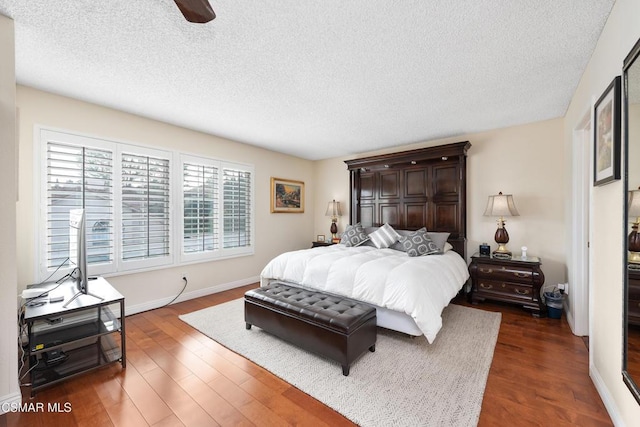 bedroom featuring ceiling fan, dark hardwood / wood-style floors, and a textured ceiling