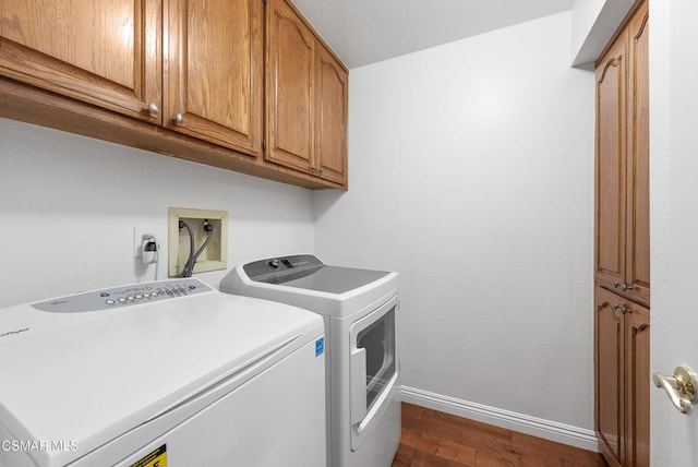 washroom featuring cabinets, washing machine and clothes dryer, and dark wood-type flooring