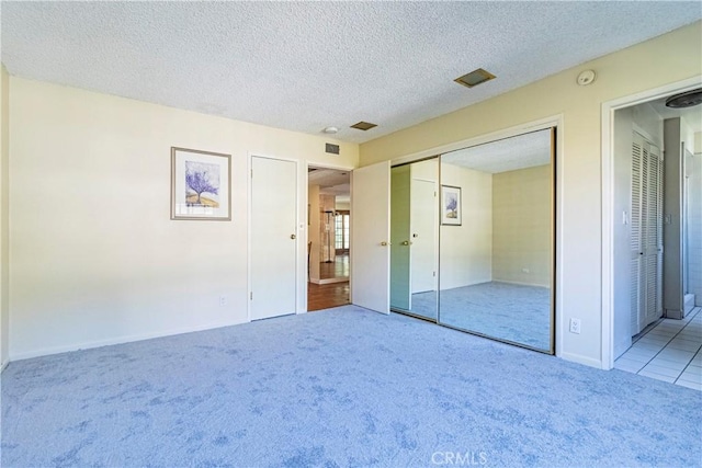 unfurnished bedroom featuring carpet floors, a textured ceiling, and a closet