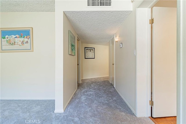 hallway with carpet floors and a textured ceiling