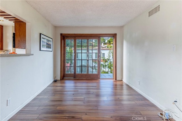 unfurnished room with dark hardwood / wood-style flooring and a textured ceiling