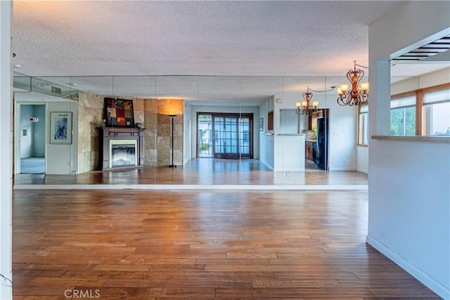 unfurnished living room featuring hardwood / wood-style flooring, a notable chandelier, and a textured ceiling