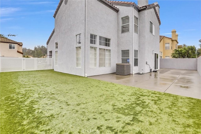 back of property with a yard, cooling unit, and a patio area