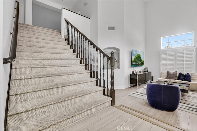 stairway with a high ceiling and hardwood / wood-style floors