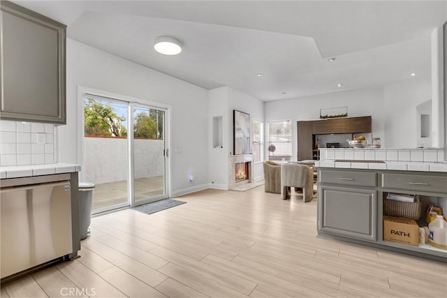 kitchen featuring tasteful backsplash, tile countertops, light hardwood / wood-style floors, and gray cabinets