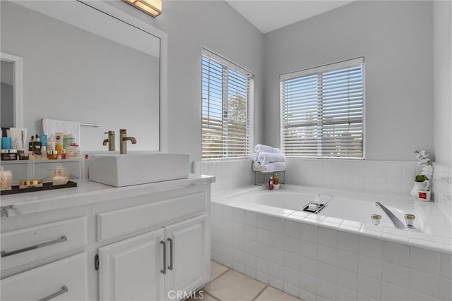 bathroom featuring tiled tub, vanity, and tile patterned floors