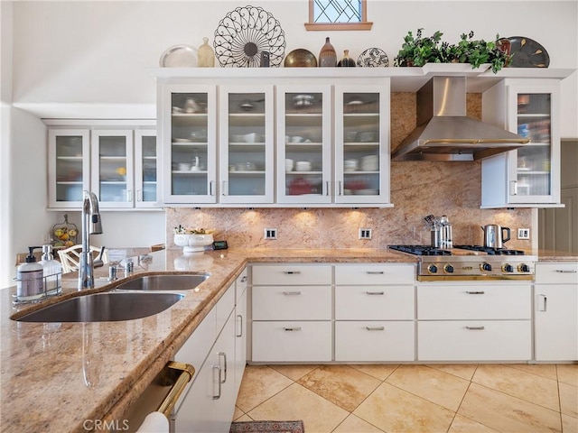 kitchen with sink, white cabinets, stainless steel gas cooktop, light stone counters, and wall chimney exhaust hood