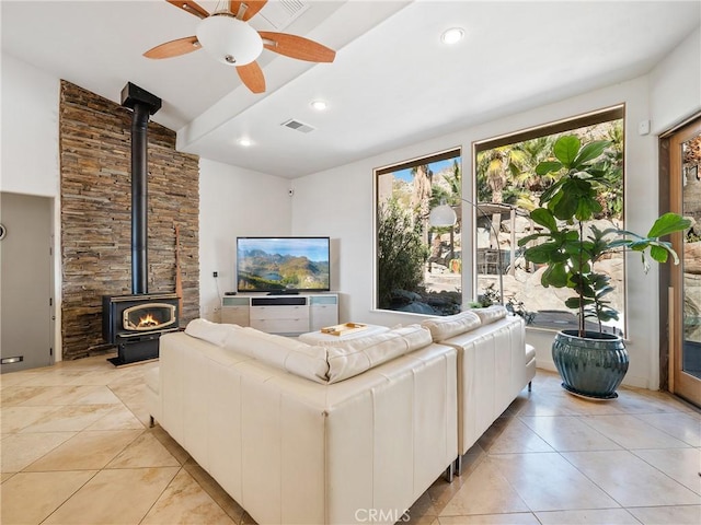 tiled living room featuring ceiling fan and a wood stove