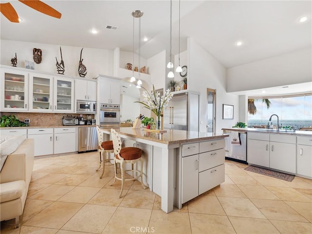 kitchen featuring appliances with stainless steel finishes, a center island, white cabinets, and decorative light fixtures