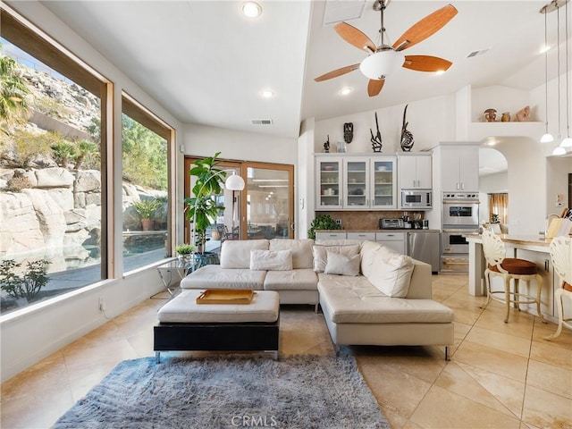 tiled living room featuring ceiling fan and high vaulted ceiling