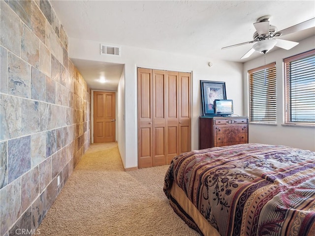 carpeted bedroom with ceiling fan, a closet, and tile walls