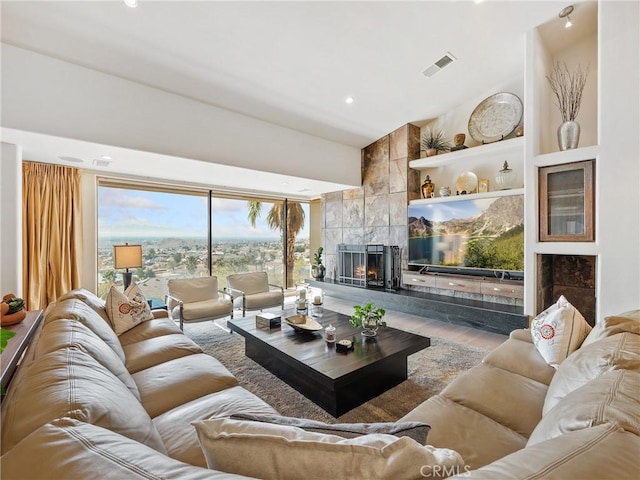 living room featuring a towering ceiling, wood-type flooring, and a tile fireplace