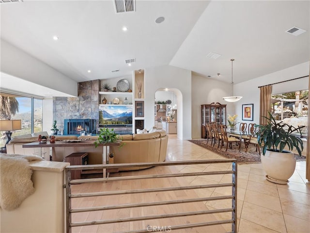 tiled living room featuring lofted ceiling, a tile fireplace, and a healthy amount of sunlight