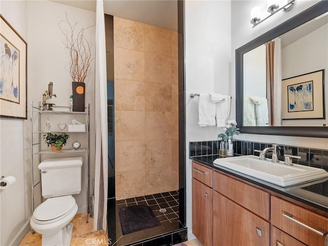 bathroom featuring backsplash, vanity, toilet, and a tile shower