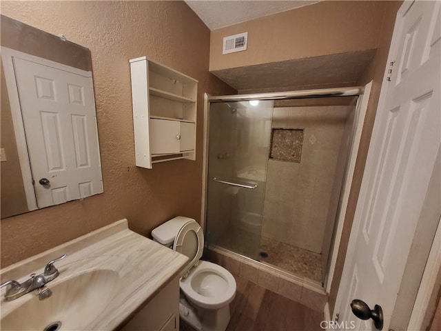 bathroom with vanity, hardwood / wood-style flooring, a shower with shower door, and toilet