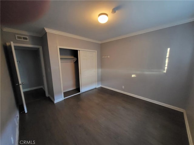 unfurnished bedroom with crown molding, dark hardwood / wood-style flooring, and a closet