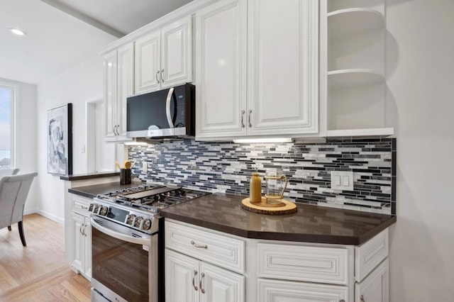 kitchen with backsplash, stainless steel gas range, and white cabinets