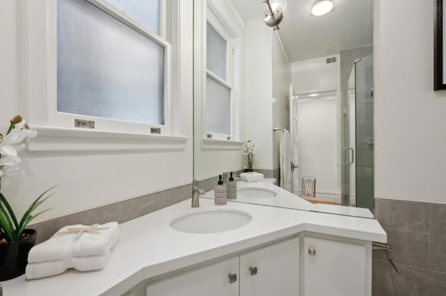 bathroom featuring vanity, a shower with door, and tile walls