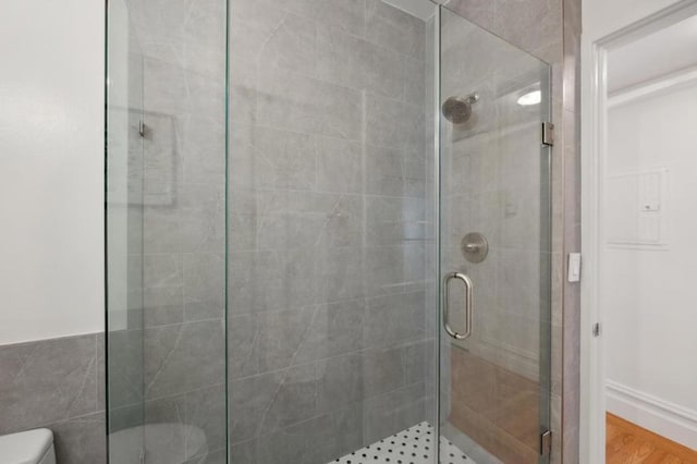 bathroom featuring hardwood / wood-style flooring, toilet, and a shower with shower door