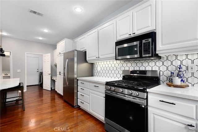 kitchen featuring white cabinetry, appliances with stainless steel finishes, backsplash, and dark hardwood / wood-style flooring