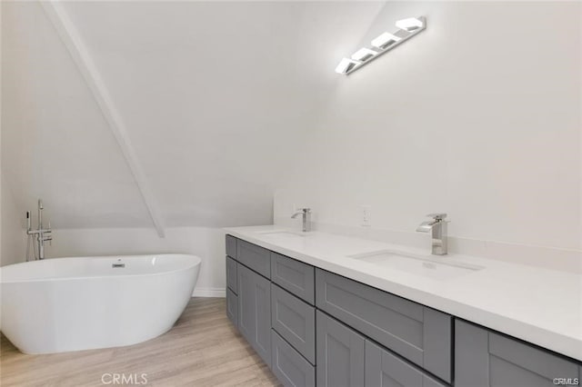 bathroom featuring a washtub, vanity, hardwood / wood-style floors, and lofted ceiling