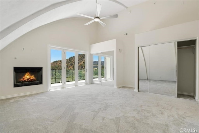 unfurnished living room with high vaulted ceiling, light colored carpet, and ceiling fan