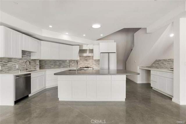 kitchen featuring wall chimney exhaust hood, fridge, stainless steel dishwasher, an island with sink, and white cabinets