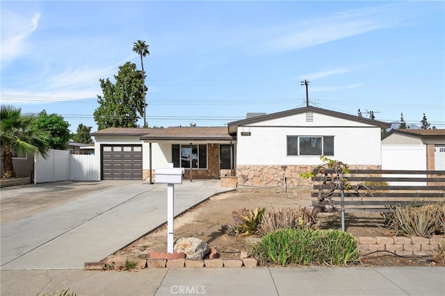 ranch-style home featuring stucco siding, stone siding, fence, concrete driveway, and an attached garage