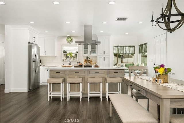 kitchen with dark hardwood / wood-style flooring, stainless steel fridge, a breakfast bar, and white cabinets