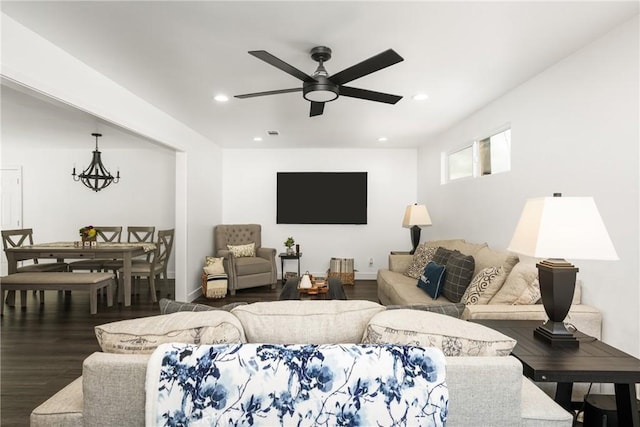 living room with ceiling fan with notable chandelier and dark hardwood / wood-style flooring