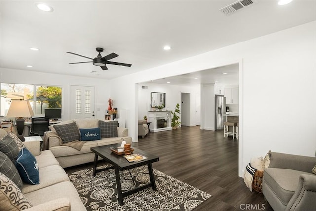 living room featuring dark wood-type flooring and ceiling fan