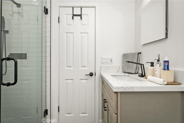 bathroom featuring a shower with door and vanity